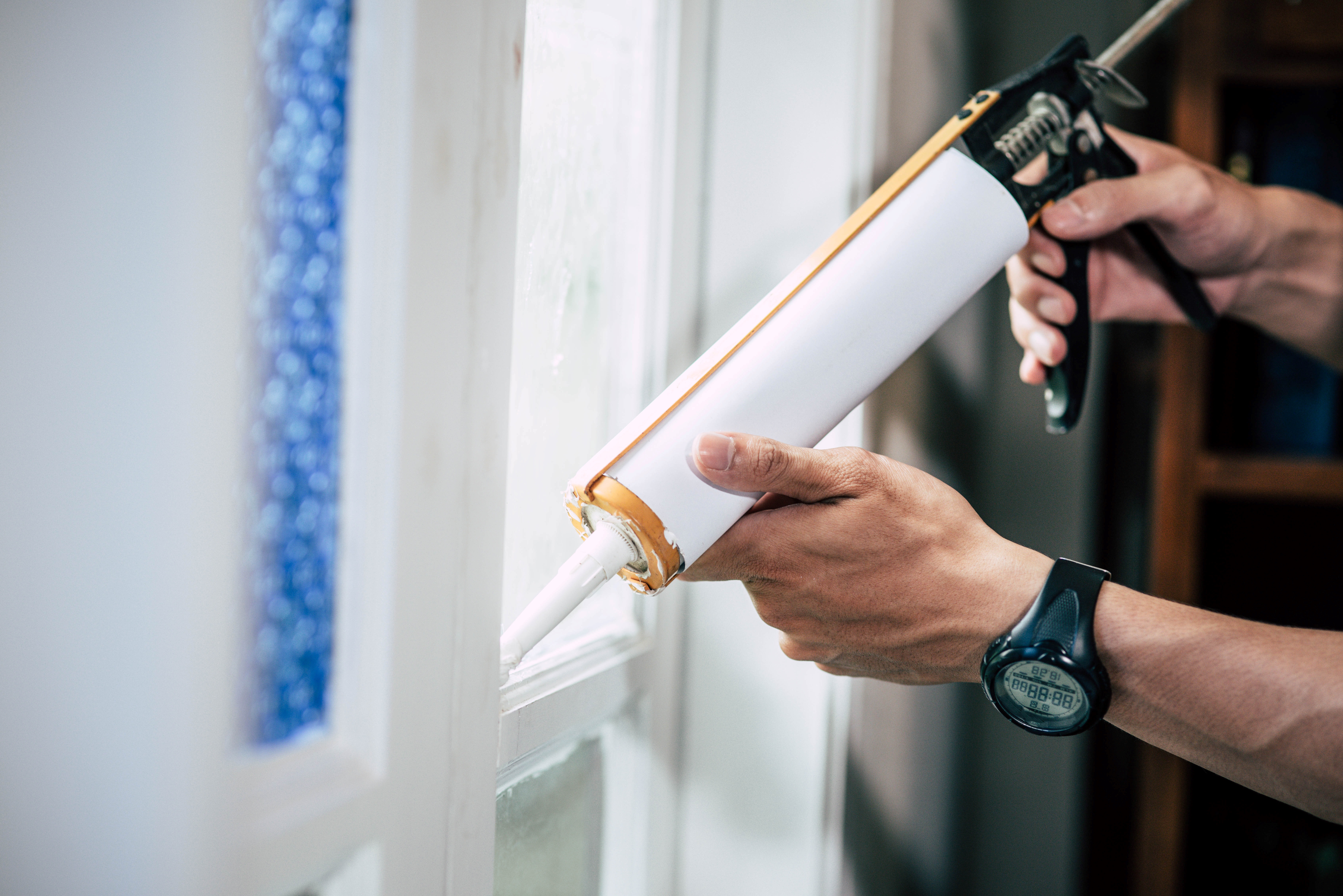 un homme qui applique de la colle sur une vitre